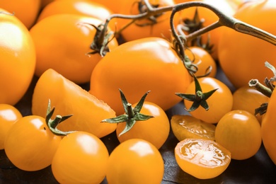 Photo of Ripe yellow tomatoes on black table, closeup