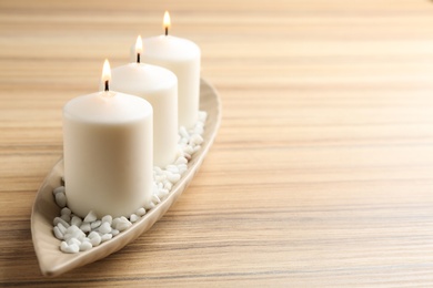 Photo of Plate with three candles on wooden table. Space for text