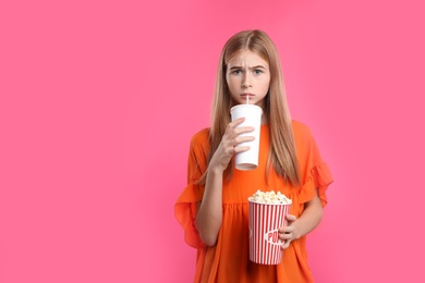 Photo of Emotional teenage girl with popcorn and beverage during cinema show on color background