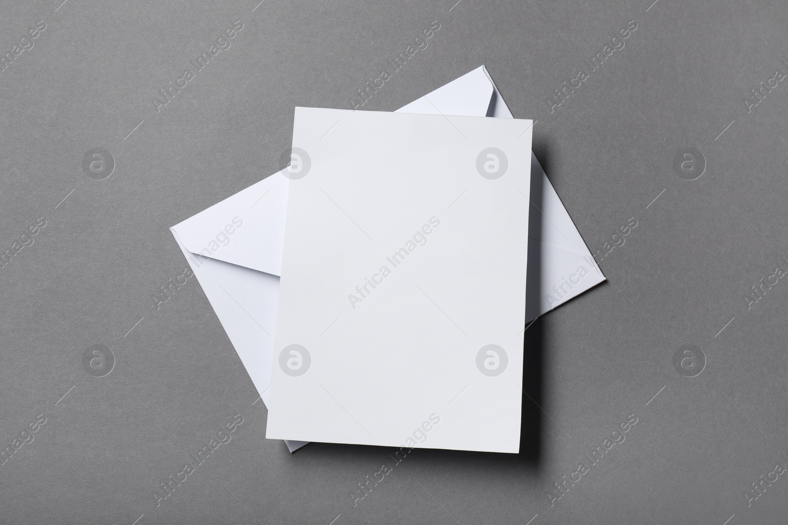 Photo of Blank sheet of paper and letter envelope on grey background, top view