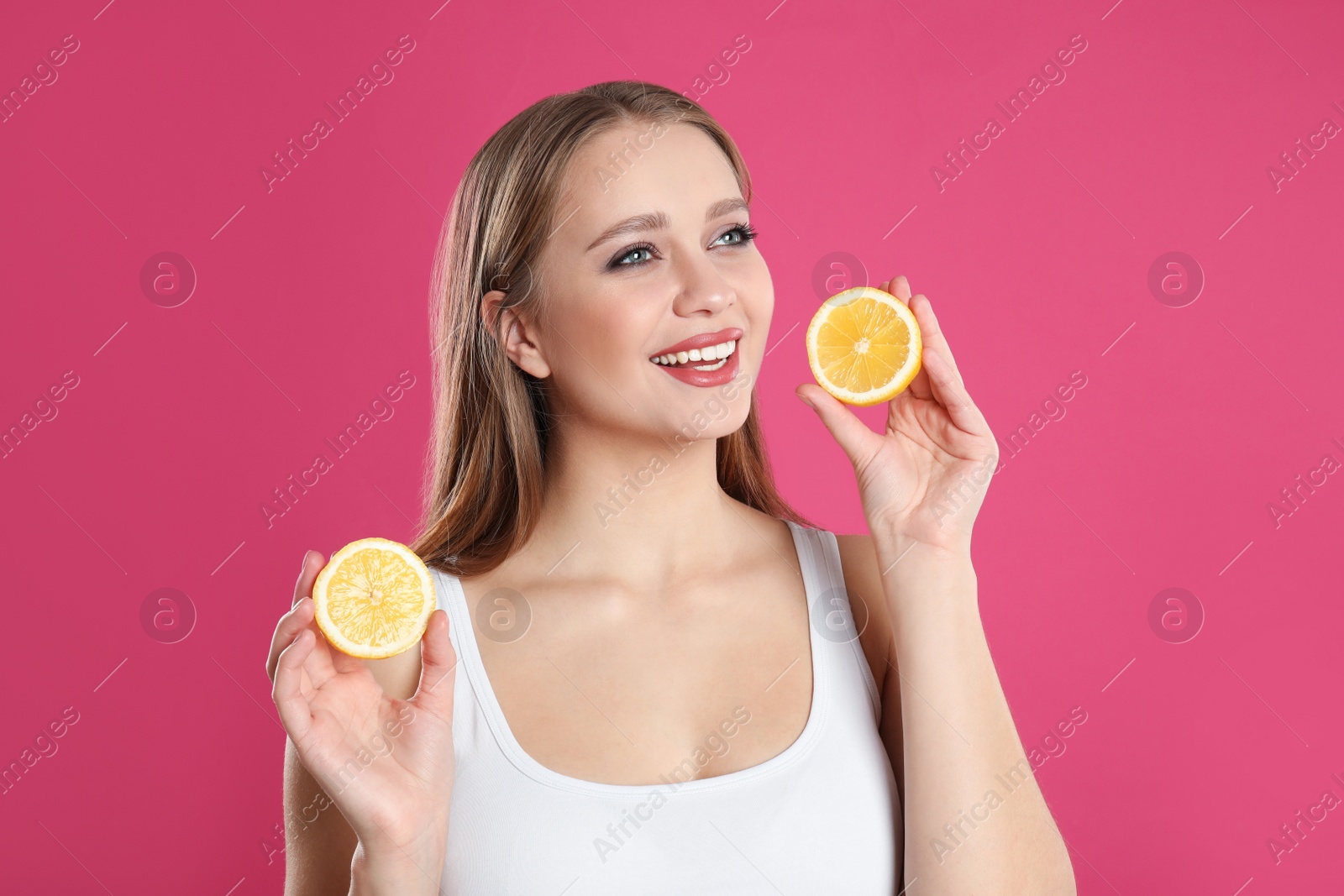 Photo of Young woman with cut lemon on pink background. Vitamin rich food