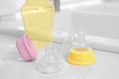 Baby bottles and nipples after washing on white countertop in kitchen