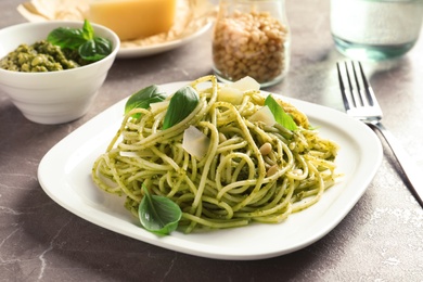 Photo of Plate with delicious basil pesto pasta on gray table