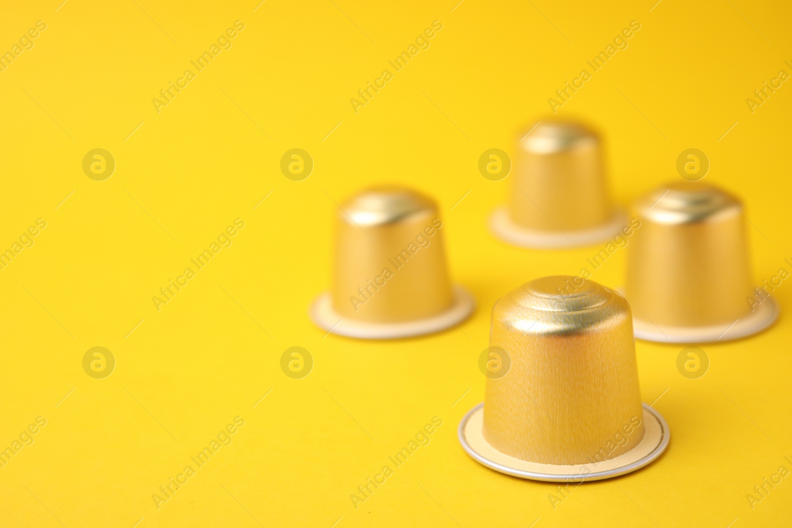 Photo of Many coffee capsules on yellow background, closeup. Space for text