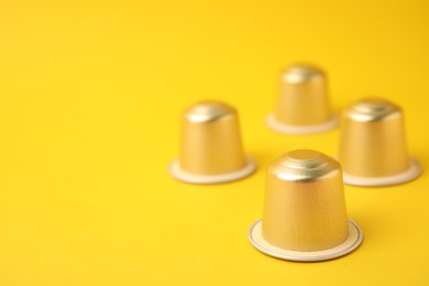 Many coffee capsules on yellow background, closeup. Space for text