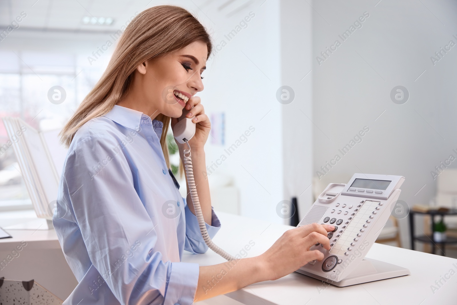Photo of Female receptionist talking on phone at hotel check-in counter