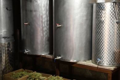 Photo of Steel tanks for wine fermentation and fresh grapes at factory