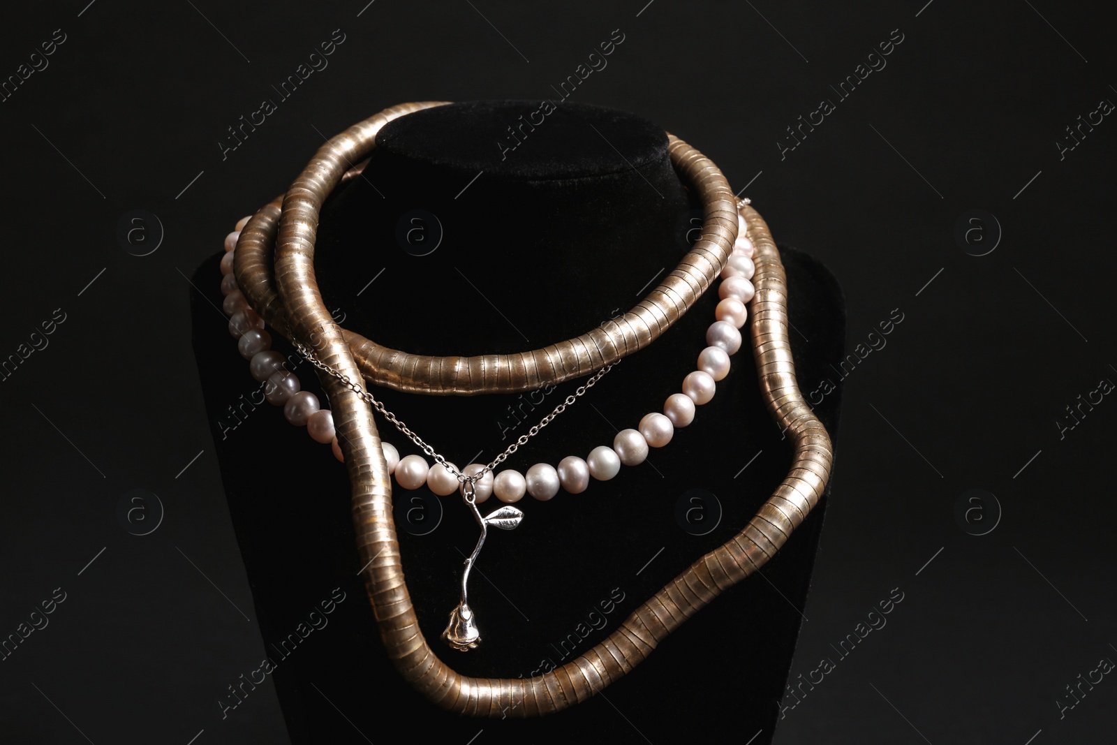 Photo of Stylish necklaces on stand against black background. Luxury jewelry