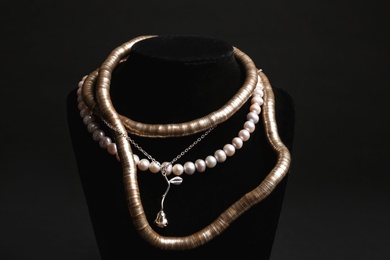 Stylish necklaces on stand against black background. Luxury jewelry