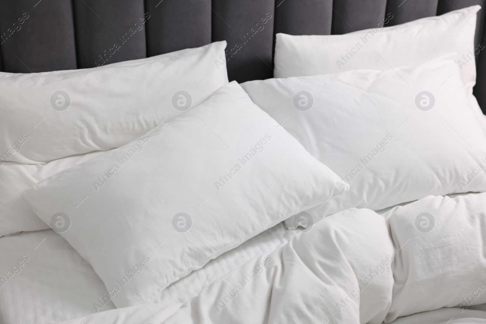 Photo of Soft white pillows and duvet on bed