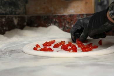 Photo of Professional chef preparing Italian pizza on table in restaurant, closeup
