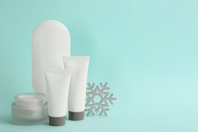 Photo of Beautiful composition with cosmetic products on cyan background, space for text. Winter care