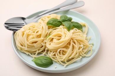 Photo of Delicious pasta with brie cheese and basil leaves on beige table, closeup