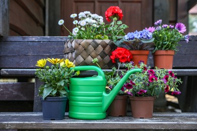 Photo of Beautiful blooming flowers and watering can on wooden stairs outdoors. Seasonal gardening