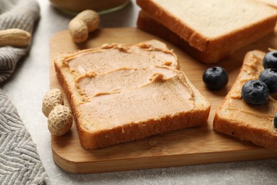 Photo of Tasty peanut butter sandwiches with fresh blueberries on table, closeup