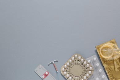 Contraceptive pills, condoms and intrauterine device on gray background, flat lay with space for text. Different birth control methods