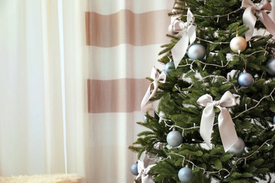 Decorated Christmas tree near window in stylish living room interior