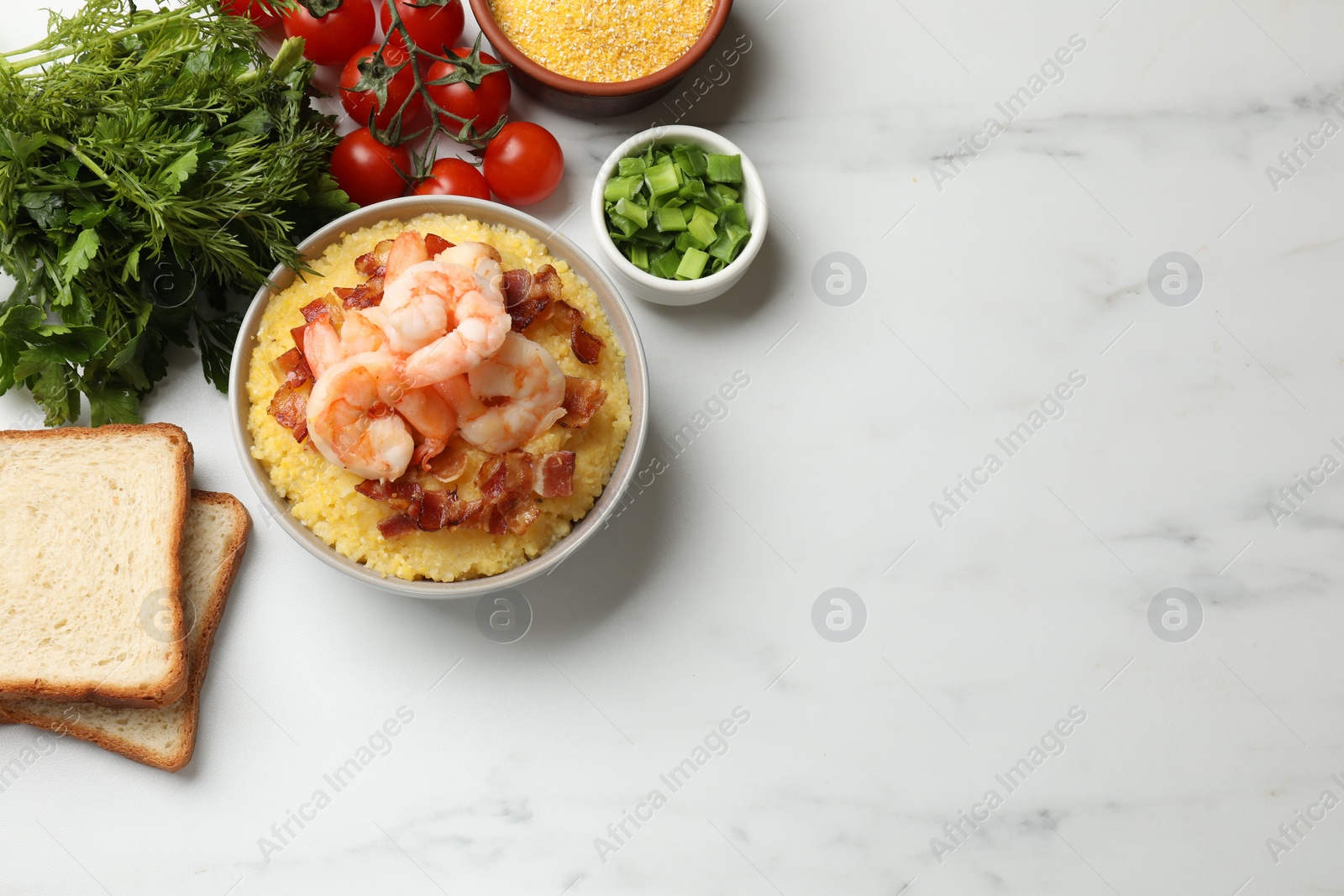 Photo of Fresh tasty shrimps, bacon and grits in bowl on white marble table, flat lay. Space for text