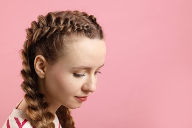 Woman with braided hair on pink background, space for text