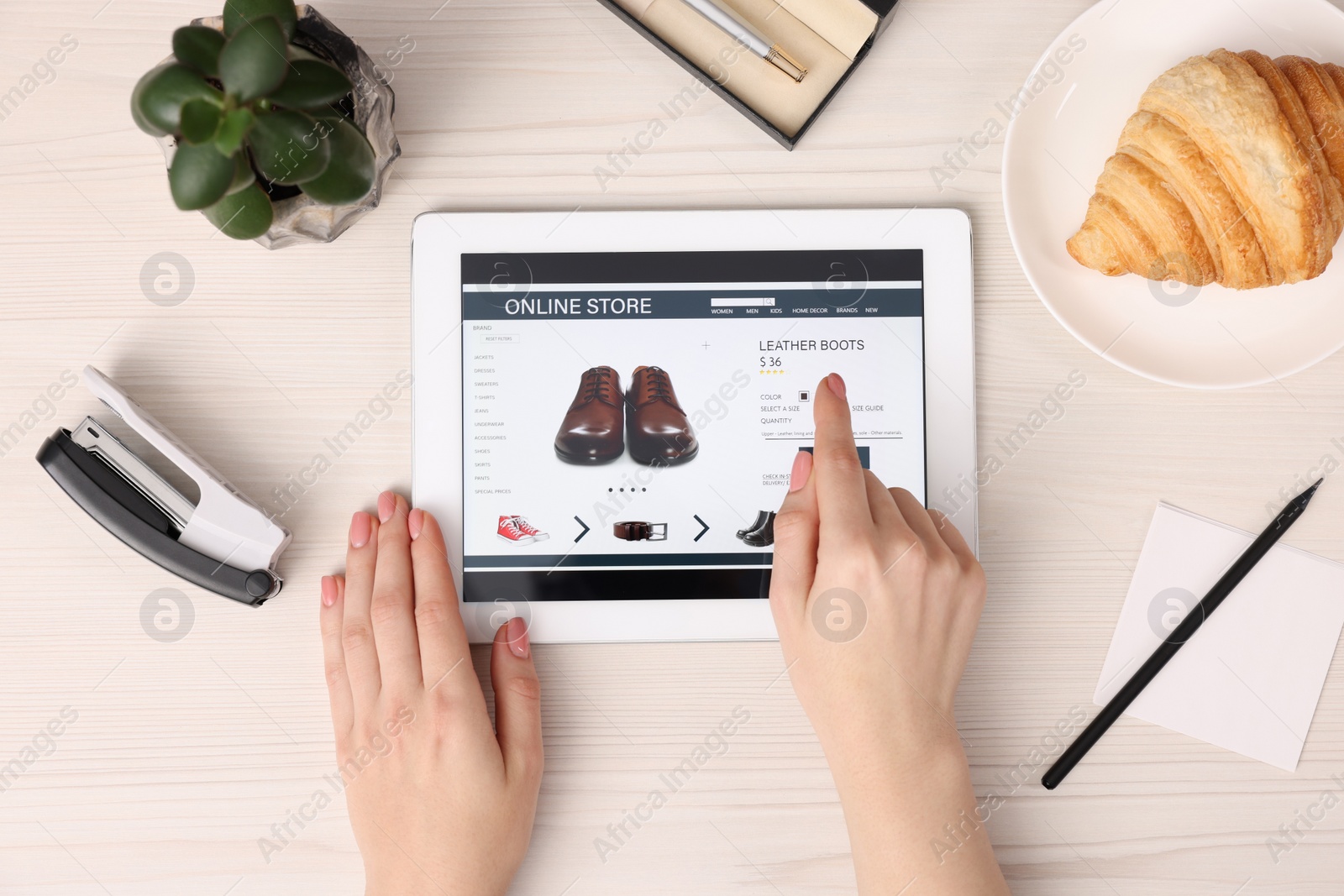 Photo of Woman with tablet shopping online at white wooden table, top view