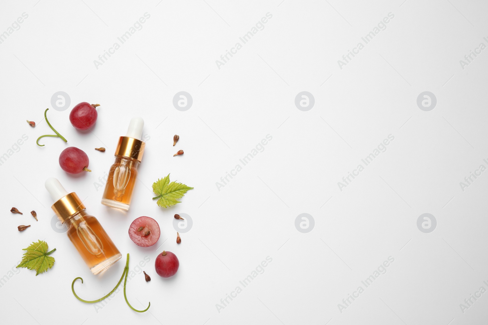 Photo of Flat lay composition with natural grape seed essential oil on white background, space for text. Organic cosmetics