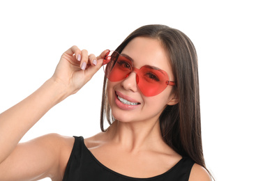 Beautiful young woman wearing heart shaped sunglasses on white background