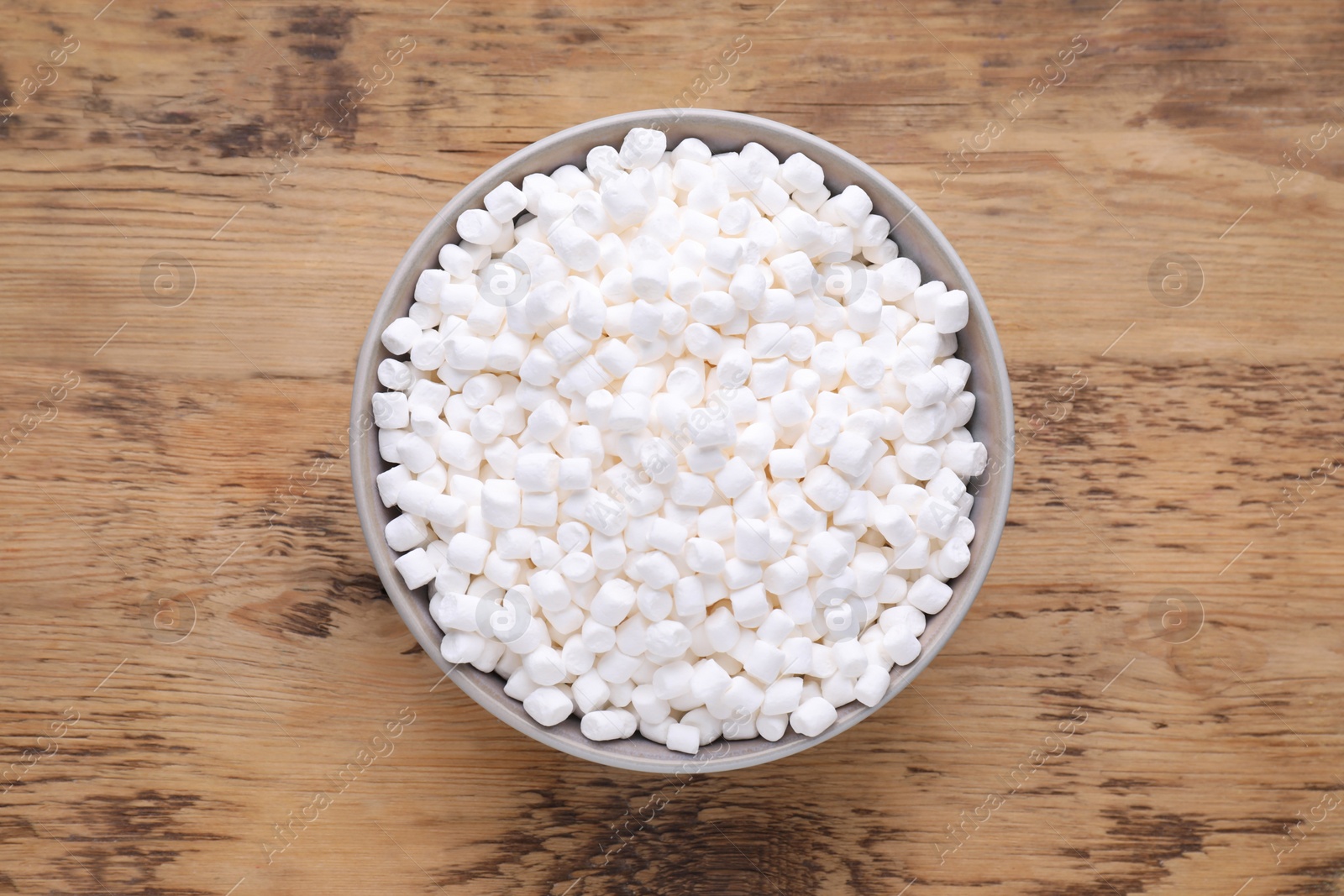 Photo of Bowl with delicious marshmallows on wooden table, top view