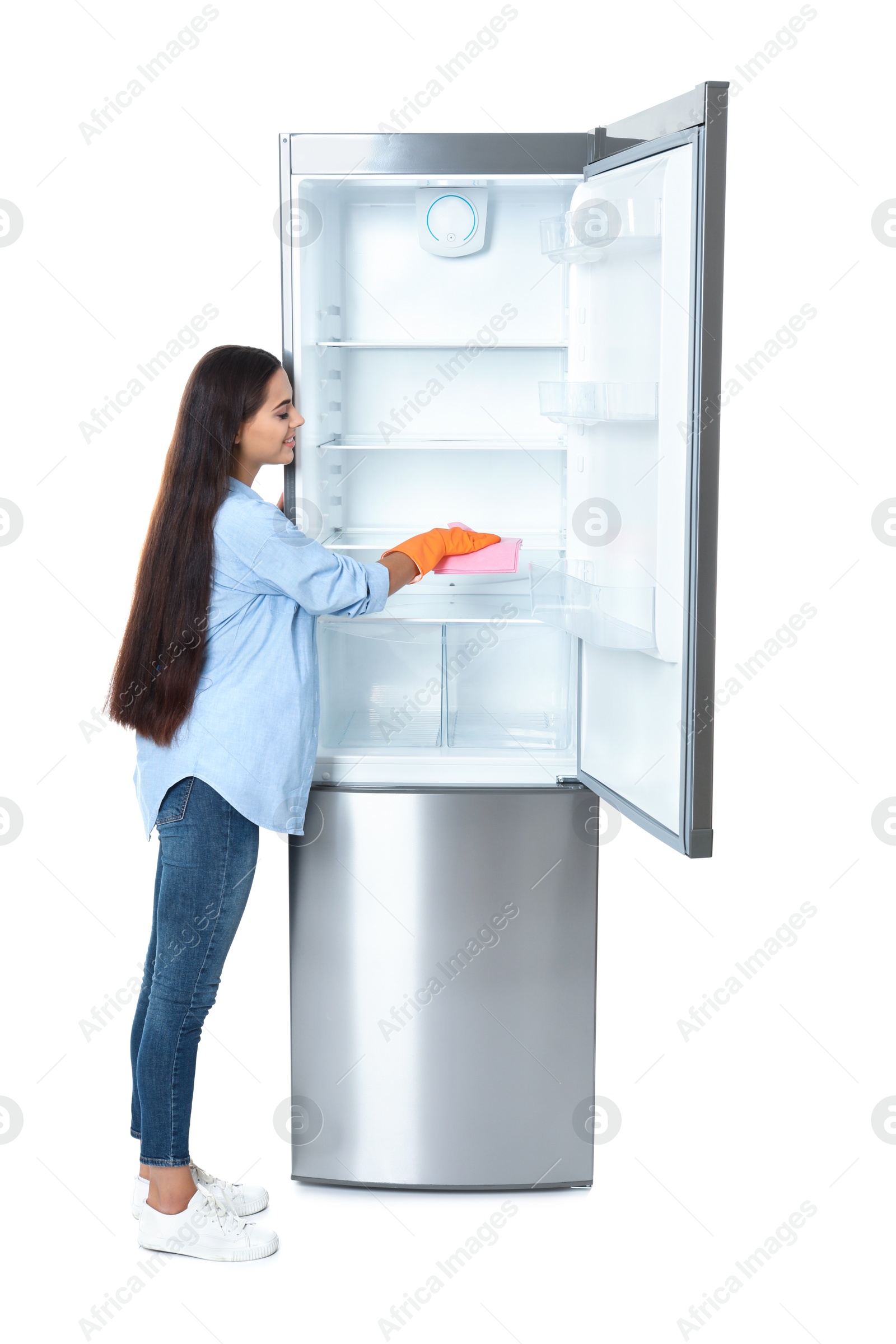 Photo of Young woman cleaning refrigerator with rag on white background