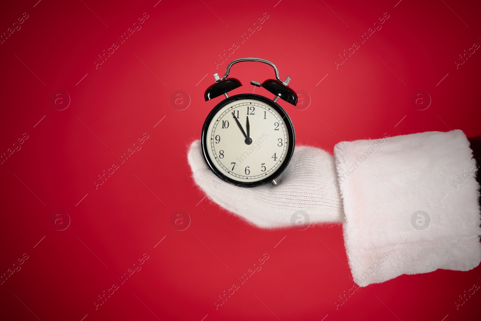 Photo of Santa Claus holding alarm clock on red background, space for text. Christmas countdown