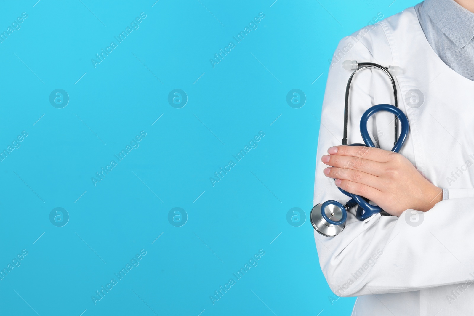 Photo of Female doctor holding stethoscope on color background, closeup with space for text