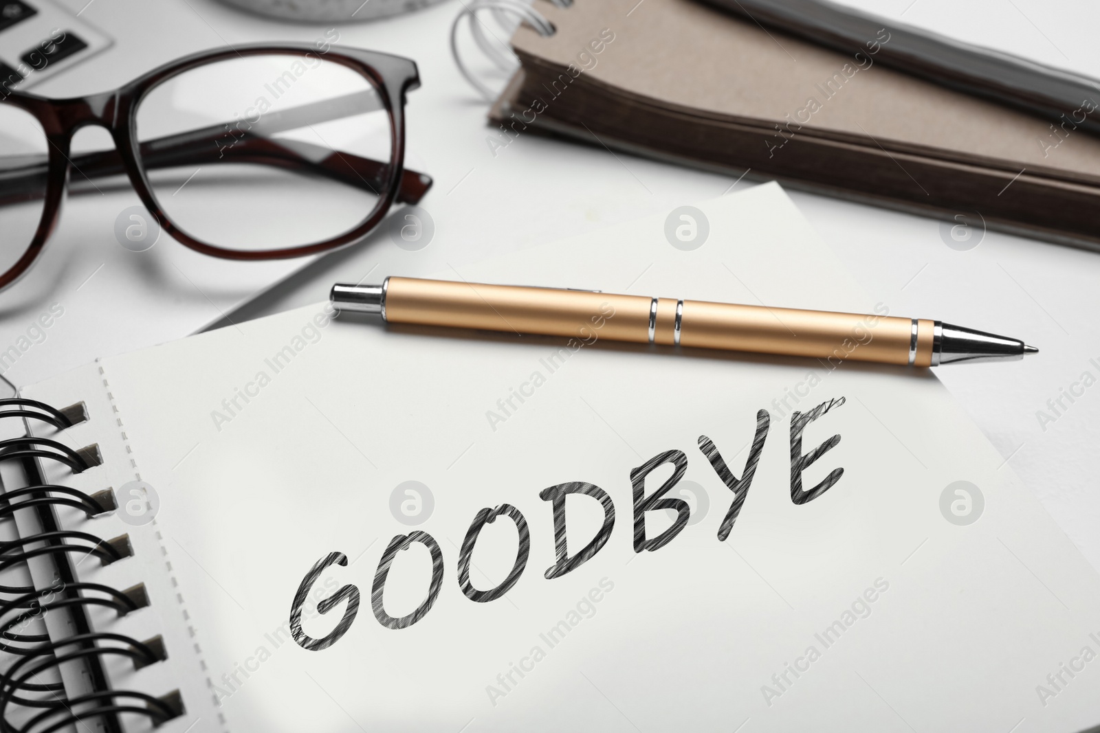 Image of Notebook with word Goodbye and pen on table, closeup