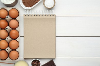 Photo of Blank recipe book and different ingredients on white wooden table, flat lay. Space for text