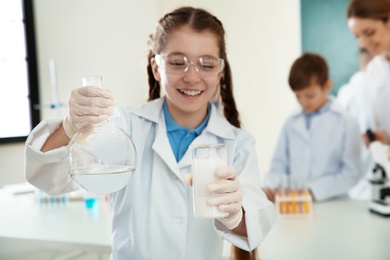 Photo of Schoolgirl making experiment in chemistry class, closeup