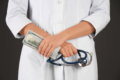 Photo of Doctor with bribe and stethoscope on black background, closeup. Corruption in medicine