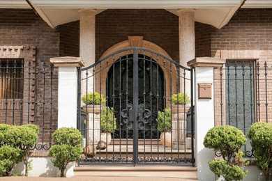Photo of Black metal gates near beautiful house and plants outdoors