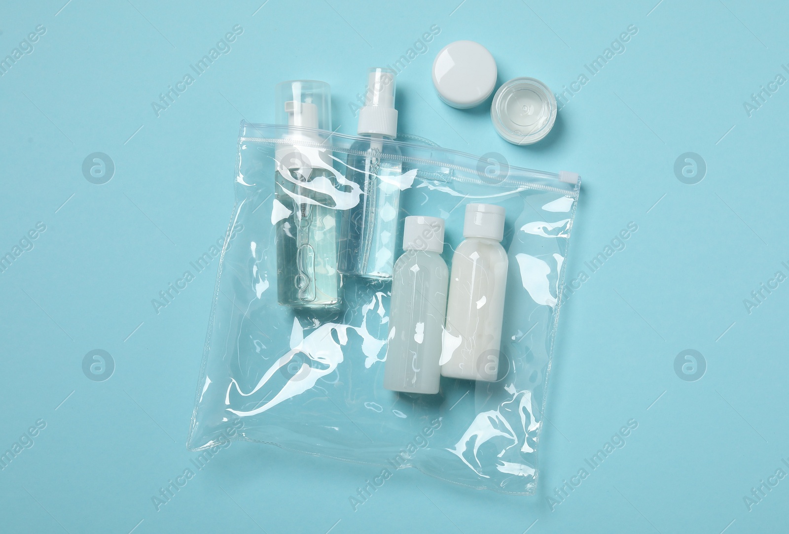 Photo of Cosmetic travel kit on light blue background, top view. Bath accessories