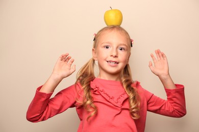 Photo of Cute little girl with apple on light background