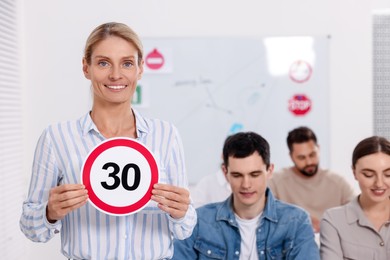 Teacher showing Speed Limit road sign during lesson in driving school
