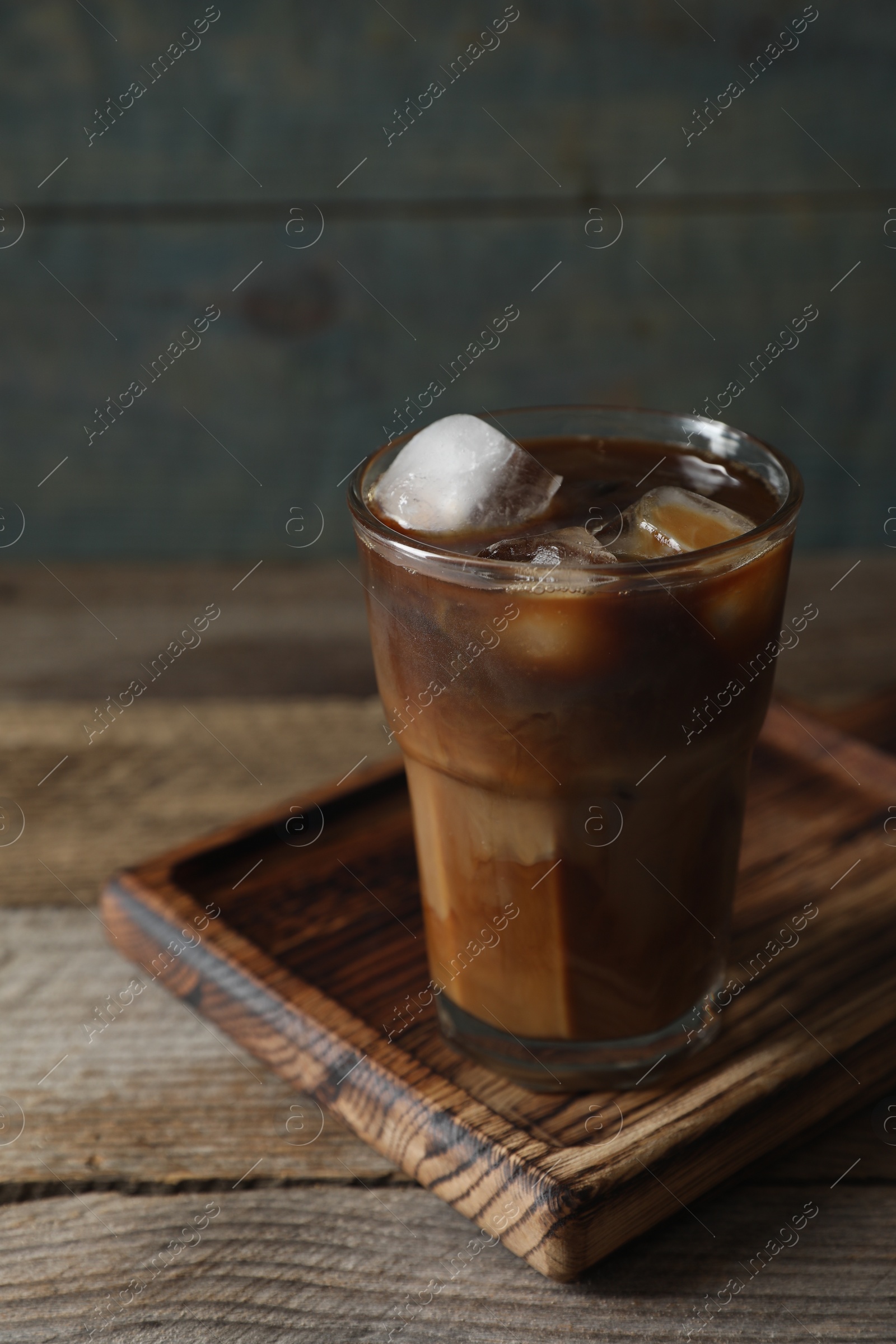 Photo of Glass of delicious iced coffee with milk on wooden table