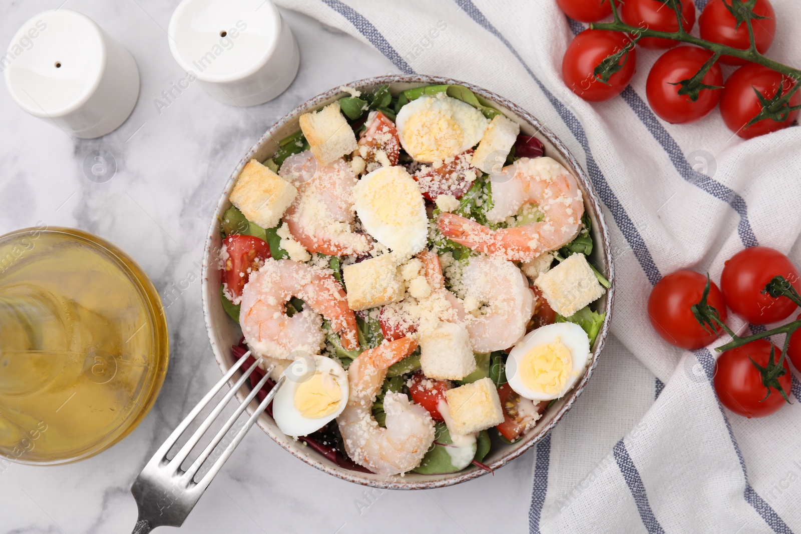 Photo of Delicious Caesar salad with shrimps served on white marble table, flat lay