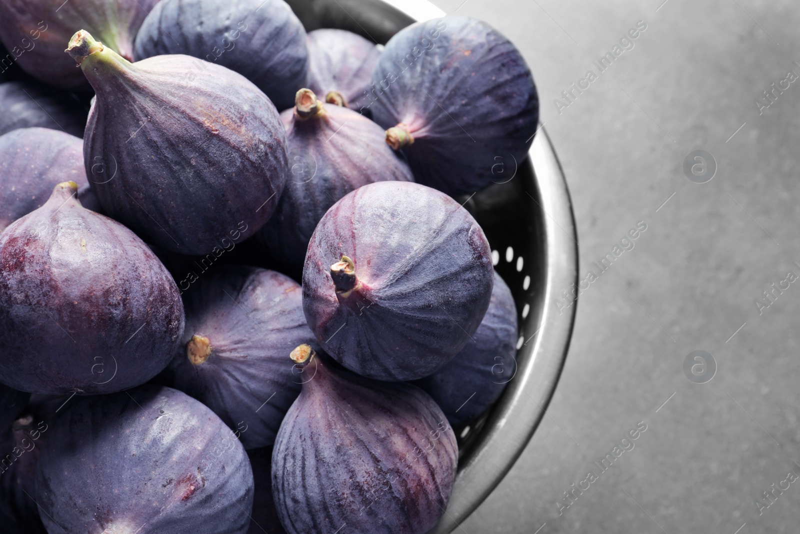 Photo of Colander with fresh ripe figs on gray background, top view