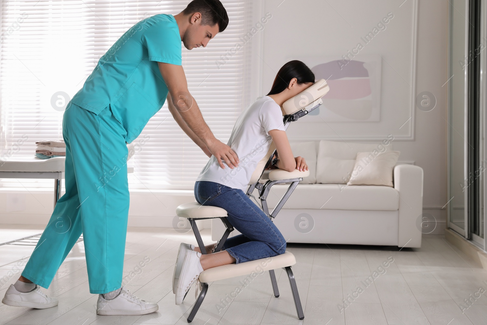 Photo of Woman receiving massage in modern chair indoors