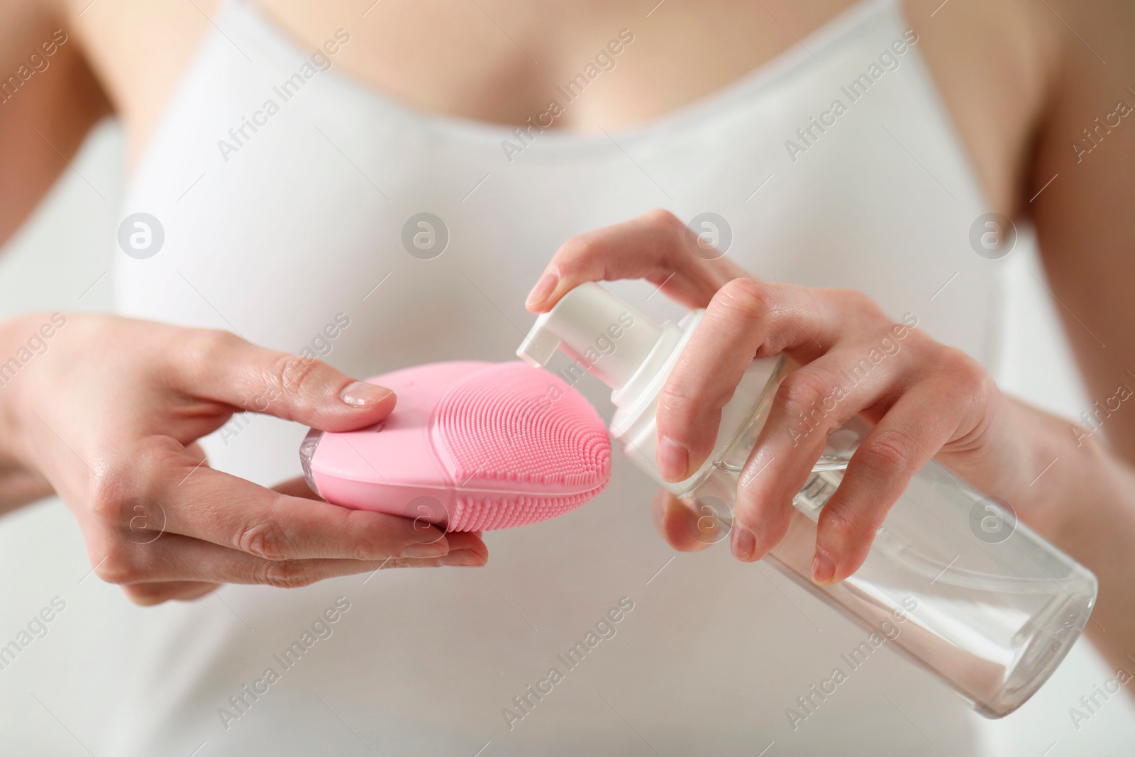 Photo of Washing face. Woman applying cleansing foam onto brush against light background, closeup