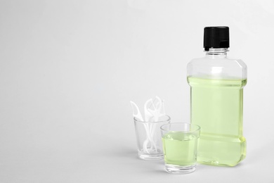 Photo of Mouthwash, dental floss and space for text on light background. Teeth care