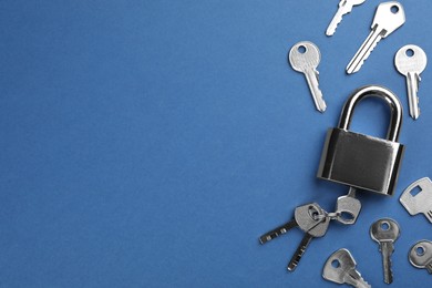 Photo of Modern padlock with keys on blue background, flat lay. Space for text