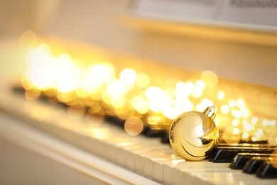 Beautiful golden bauble and fairy lights on piano keys, space for text. Christmas music