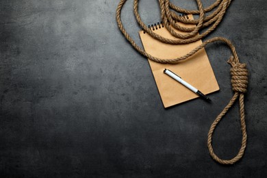 Photo of Rope noose and blank notebook with pen on grey table, flat lay. Space for text