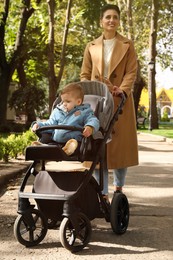 Happy mother walking with her son in stroller outdoors