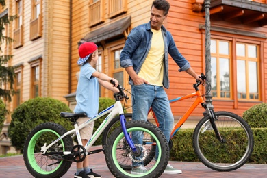 Dad teaching son to ride bicycle outdoors