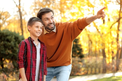 Photo of Happy father and son spending time in park. Autumn walk